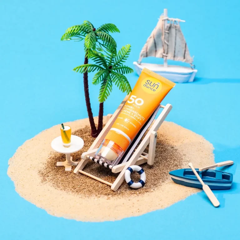 Miniaturszene mit Sonnenschutz Stift in einem Liegestuhl auf einer kleinen Insel mit Sandstrand, Palmen, Cocktail, Ruderboot und Segelschiff im Hintergrund. Studio für Produktfotografie Klaus Ohlenschlaeger, Frankfurt-Kronberg
