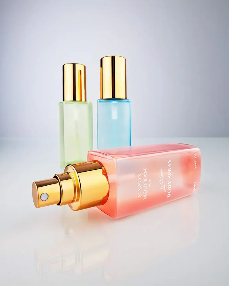 Eine rote Flasche Body-Spray im Vordergrund quer liegend mit zwei weiteren Flaschen in grün und blau im Hintergrund. Ein kurzer Aufnahmeabstand sorgt für eine dynamische Perspektive. Studio für Produktfotografie Klaus Ohlenschläger