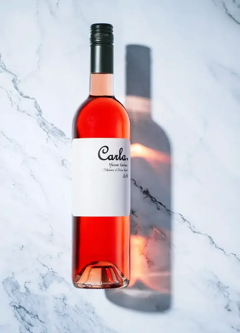 Eine Flasche Rose-Wein liegt auf einem Hintergrund aus Marmor. Sie wirft einen transparenten Schatten mit rosefarbenen Reflexen nach rechts. Produktfotografie Klaus Ohlenschläger, Frankfurt-Kronberg