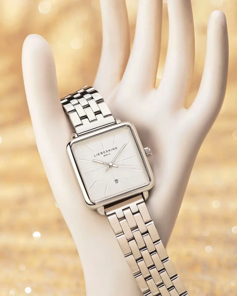 Produktfoto einer Armbanduhr für Damen, die auf einer Schmuckhand vor sandfarbenem Hintergrund drappiert ist. Fotograf Klaus Ohlenschläger, Frankfurt-Kronberg